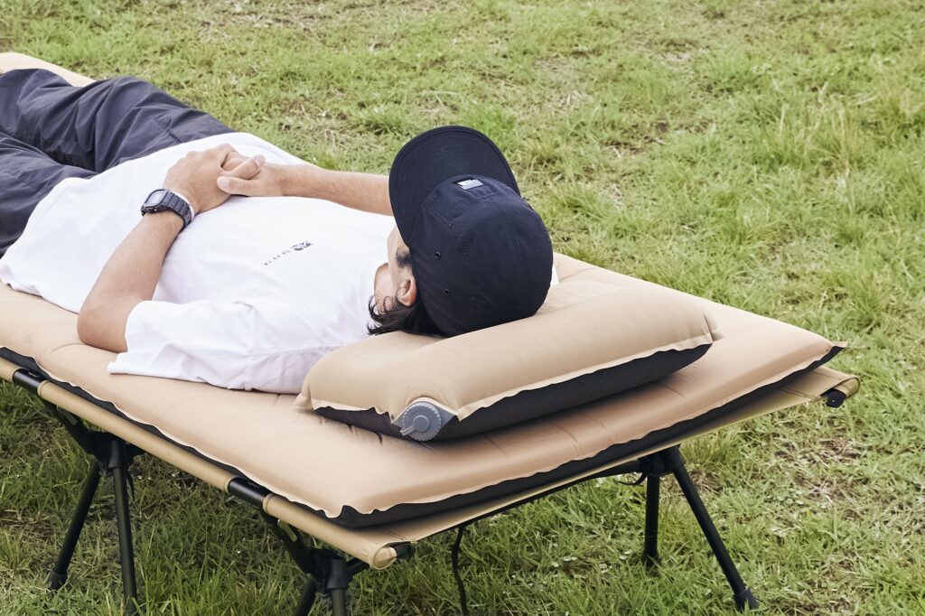 キャンプマット＆コット＆キャンプ用枕を使って寝転ぶ男性