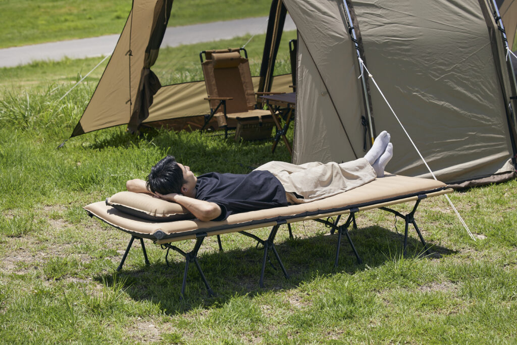キャンプマットの上で仰向けに寝転ぶ男性