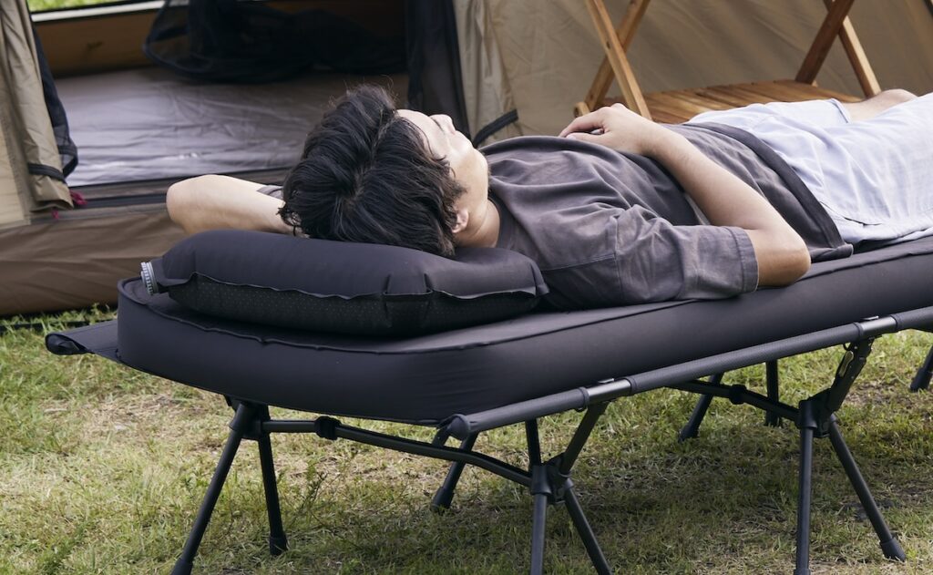 コット＆キャンプマットの上で、枕ありで寝転ぶ男性