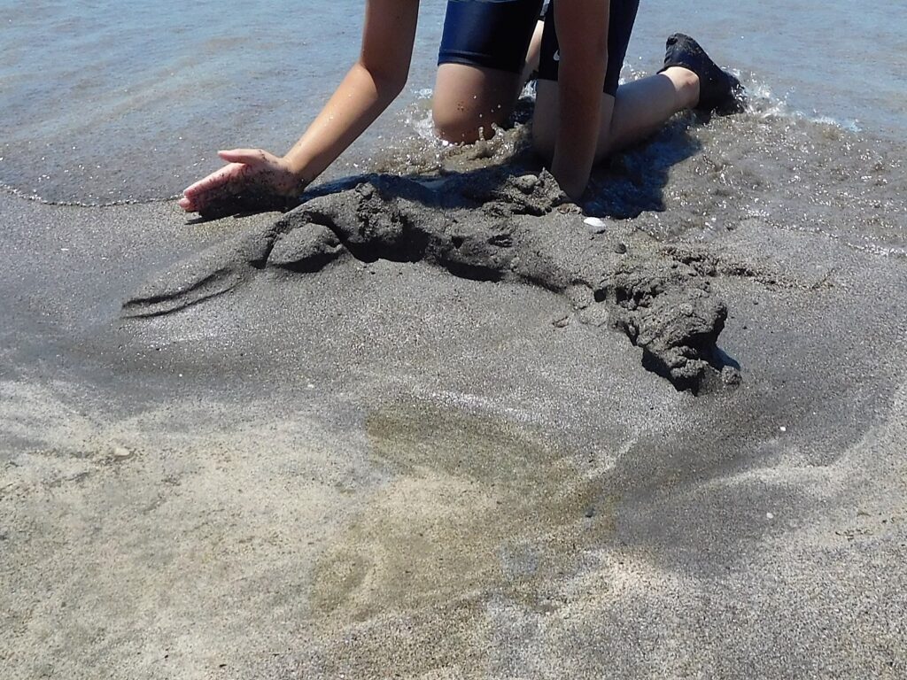 水際で砂遊びをする子ども