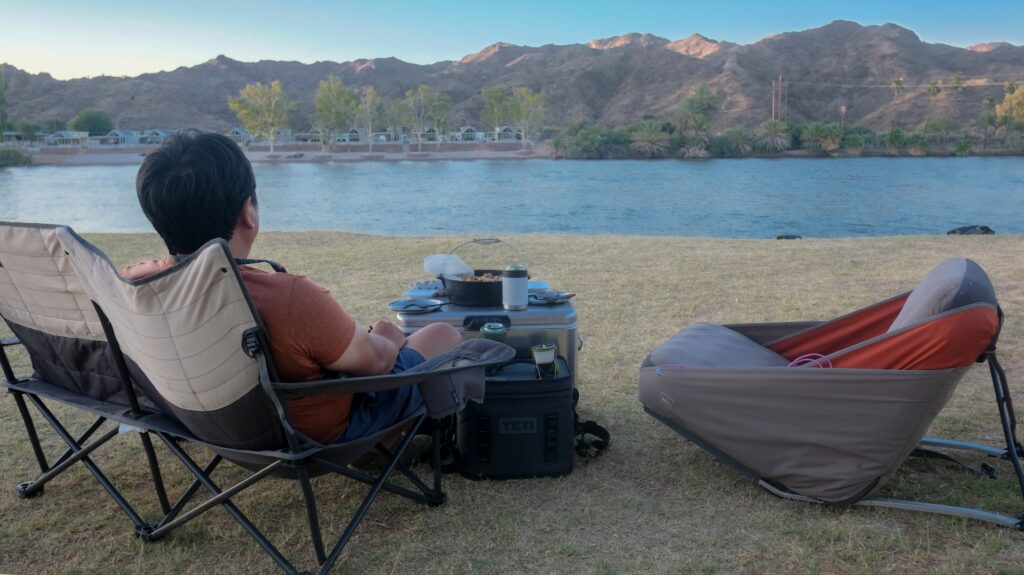 キャンプ用の椅子に腰をかけて景色を眺める男性